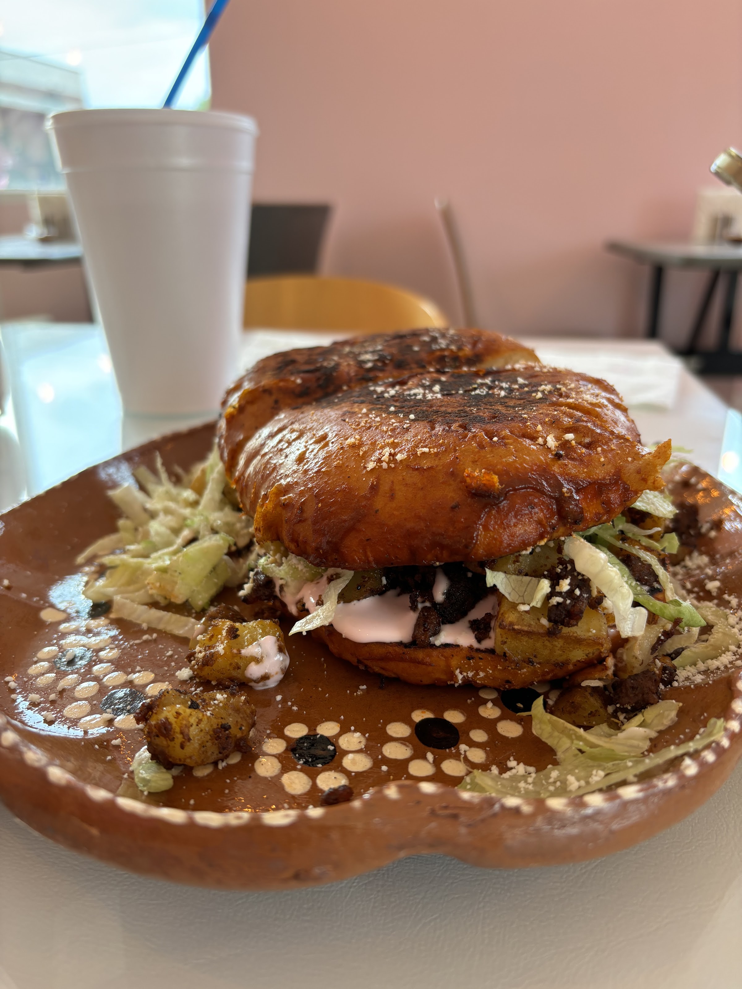 Guajillo-red dipped pambazo torta stacked with meat and crema on a clay plate